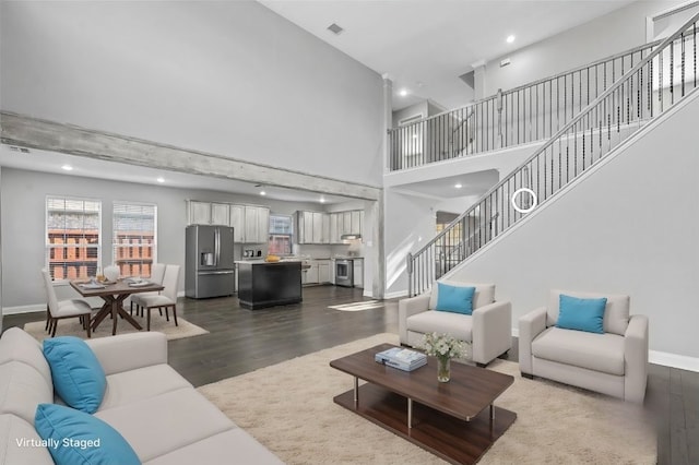 living room with a towering ceiling and wood-type flooring