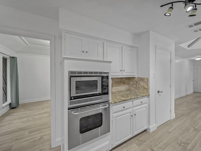 kitchen with appliances with stainless steel finishes, tasteful backsplash, white cabinets, light stone counters, and light hardwood / wood-style floors