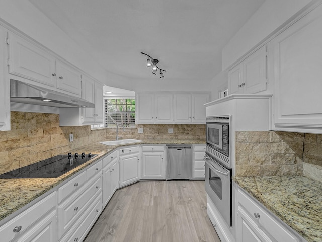 kitchen featuring sink, appliances with stainless steel finishes, tasteful backsplash, white cabinets, and wall chimney exhaust hood