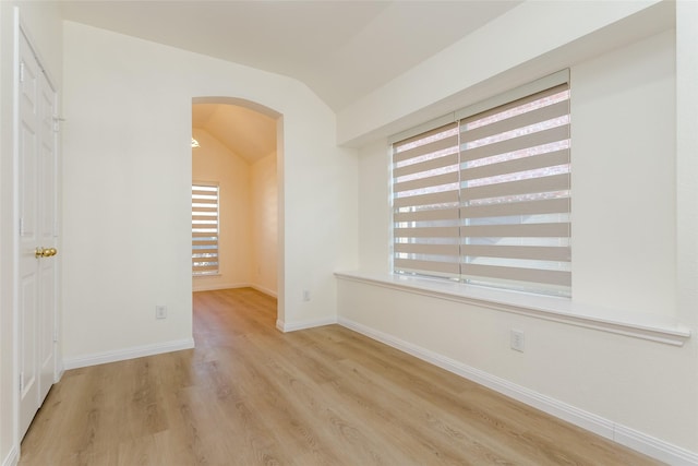 empty room with light hardwood / wood-style flooring and vaulted ceiling