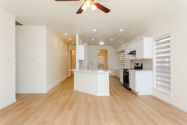 kitchen with sink, tasteful backsplash, white cabinets, stainless steel range with electric cooktop, and light wood-type flooring