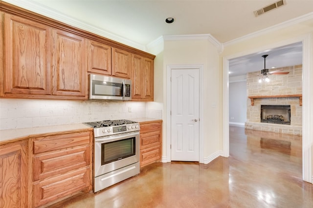 kitchen featuring pendant lighting, appliances with stainless steel finishes, tasteful backsplash, a fireplace, and ornamental molding