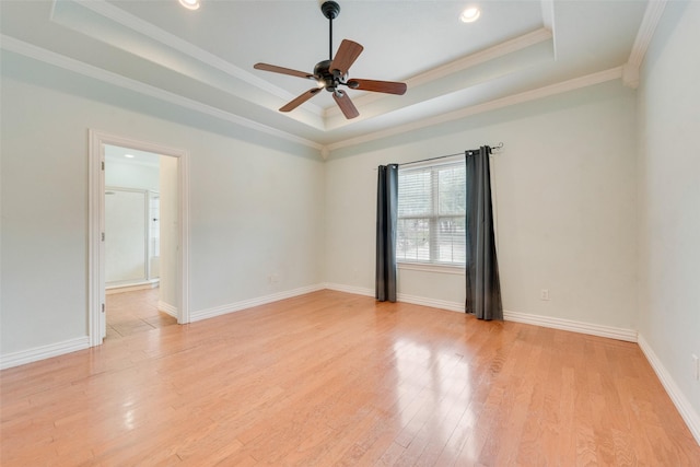 unfurnished room featuring crown molding, a tray ceiling, light hardwood / wood-style flooring, and ceiling fan