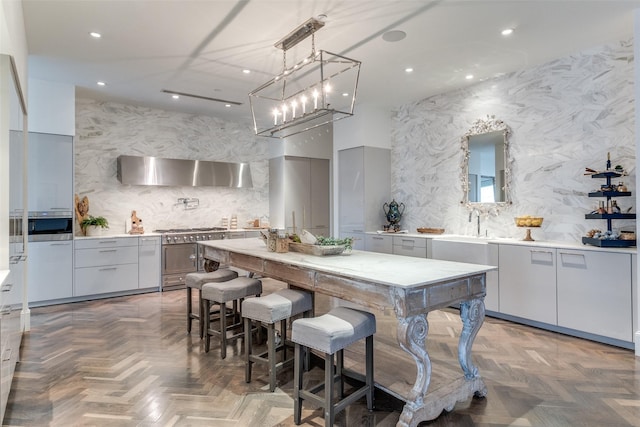 kitchen featuring exhaust hood, decorative light fixtures, parquet floors, double oven range, and backsplash