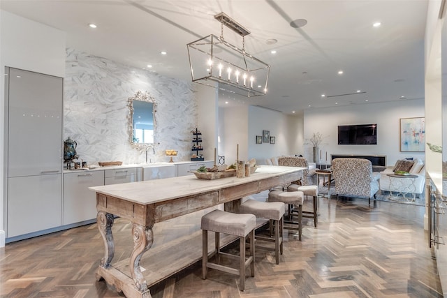 bar featuring pendant lighting, tasteful backsplash, white cabinets, and parquet flooring