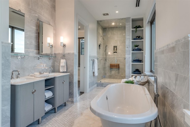 bathroom featuring plus walk in shower, tile walls, vanity, and tile patterned floors