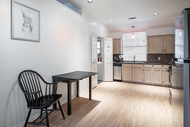 kitchen with pendant lighting, sink, backsplash, stainless steel dishwasher, and light wood-type flooring