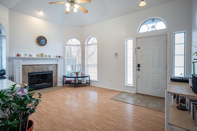 foyer entrance with ceiling fan, a healthy amount of sunlight, a fireplace, and light hardwood / wood-style flooring