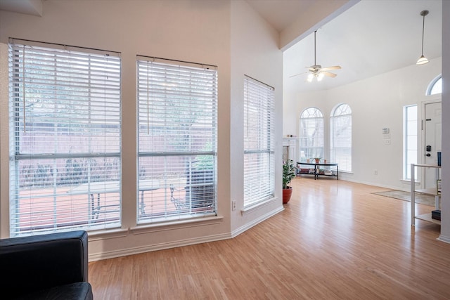 entryway with high vaulted ceiling, ceiling fan, and light hardwood / wood-style flooring