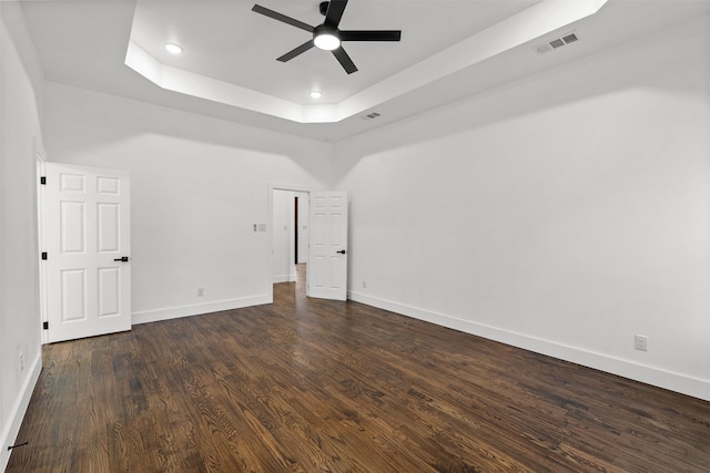 unfurnished bedroom with a tray ceiling, dark hardwood / wood-style floors, and ceiling fan