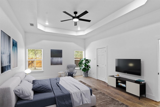 bedroom featuring dark wood-type flooring, ceiling fan, and a tray ceiling