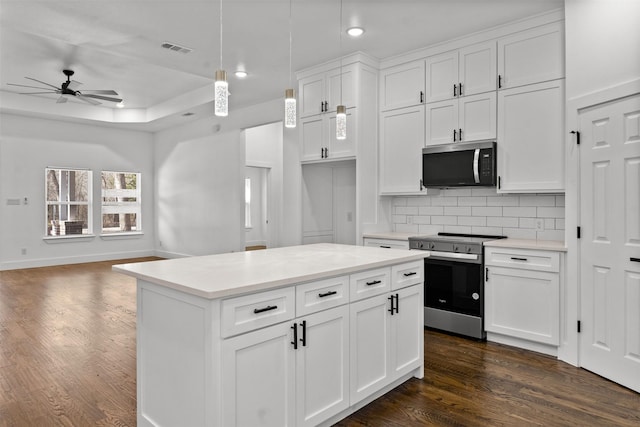 kitchen with hanging light fixtures, stainless steel appliances, dark hardwood / wood-style floors, white cabinets, and decorative backsplash