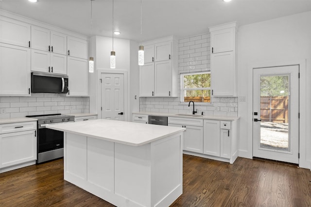 kitchen featuring hanging light fixtures, white cabinetry, appliances with stainless steel finishes, and a center island