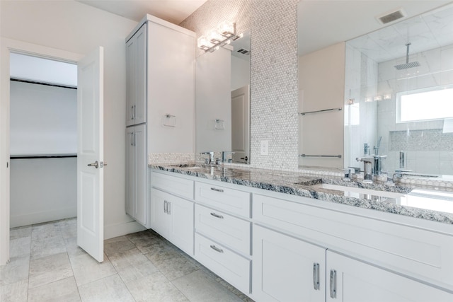 full bath featuring double vanity, visible vents, a spacious closet, a sink, and walk in shower