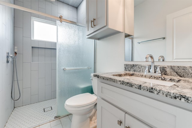 full bathroom featuring tile patterned flooring, tiled shower, vanity, and toilet