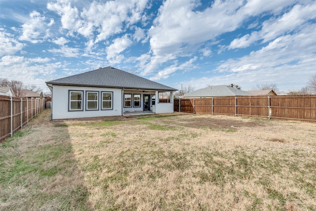 rear view of house featuring a patio area, a fenced backyard, a lawn, and stucco siding