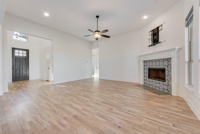 unfurnished living room with ceiling fan, a fireplace, and light hardwood / wood-style floors