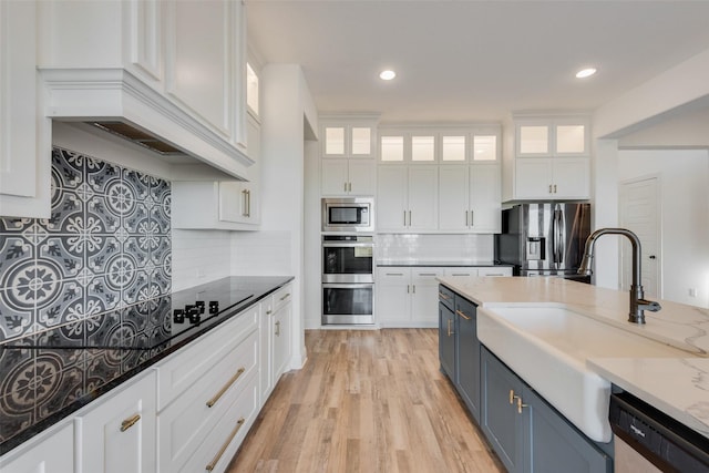 kitchen featuring blue cabinetry, sink, white cabinetry, appliances with stainless steel finishes, and dark stone counters