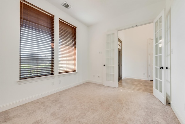 carpeted spare room featuring french doors