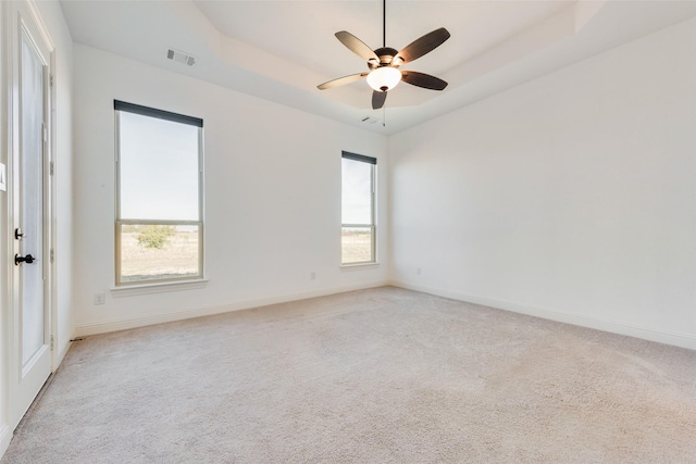 carpeted empty room with a raised ceiling and ceiling fan