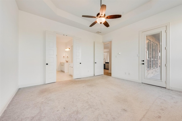 empty room featuring light colored carpet, ceiling fan, and a tray ceiling