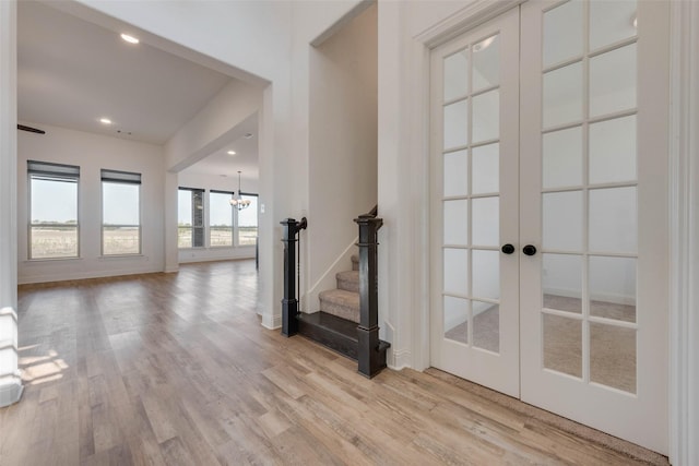 unfurnished living room with french doors, light hardwood / wood-style floors, and a notable chandelier