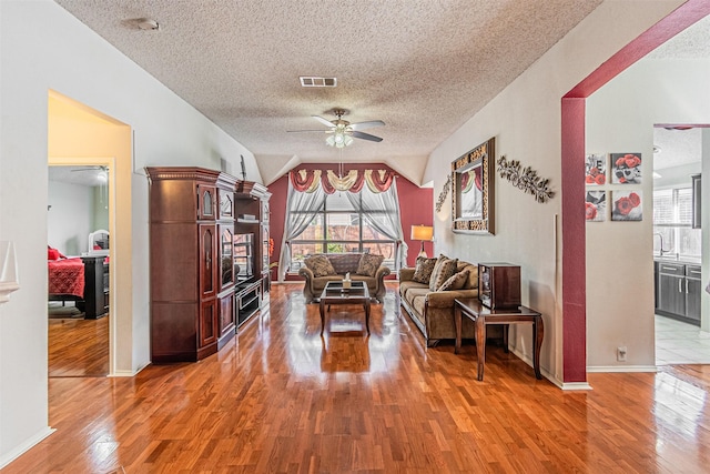 living room featuring ceiling fan, hardwood / wood-style floors, and a wealth of natural light