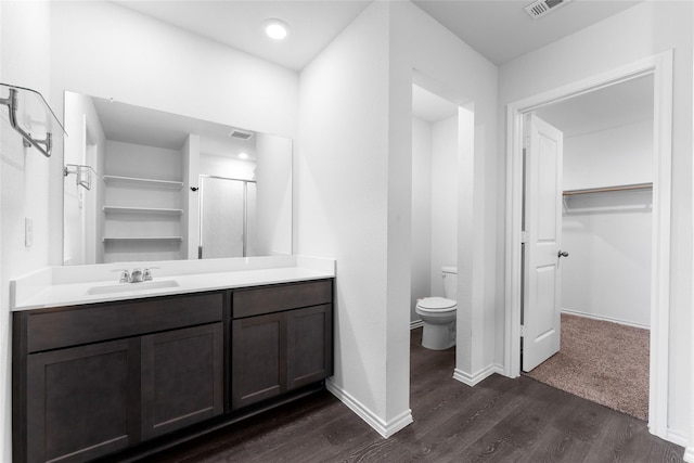 bathroom featuring a shower with door, wood-type flooring, vanity, and toilet