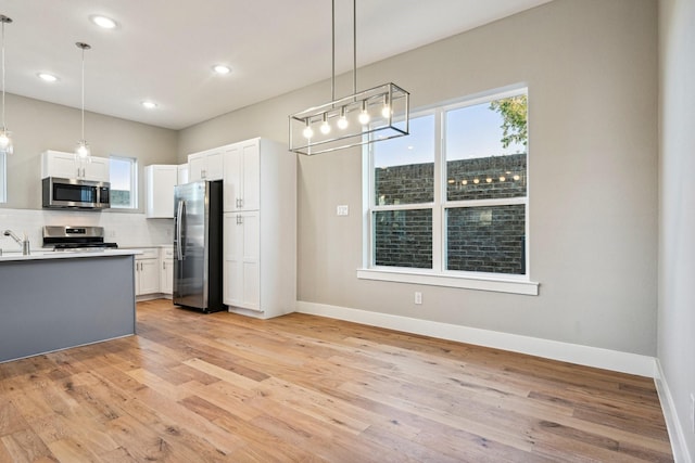 kitchen with decorative light fixtures, stainless steel appliances, and white cabinets