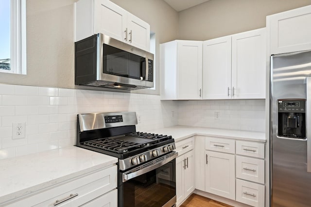 kitchen featuring backsplash, appliances with stainless steel finishes, and white cabinets