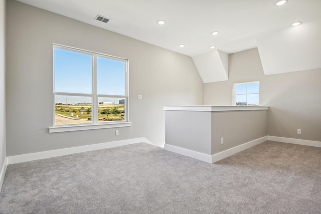 carpeted spare room with vaulted ceiling