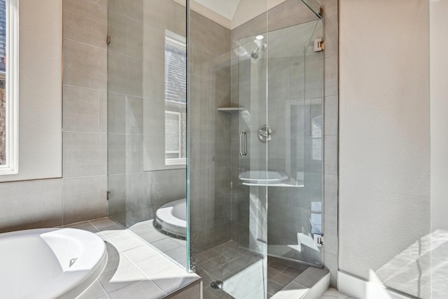 bathroom featuring independent shower and bath and tile walls