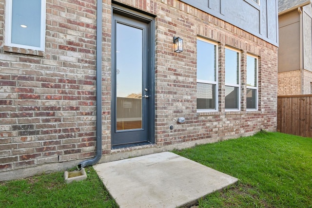 entrance to property featuring a patio and a yard