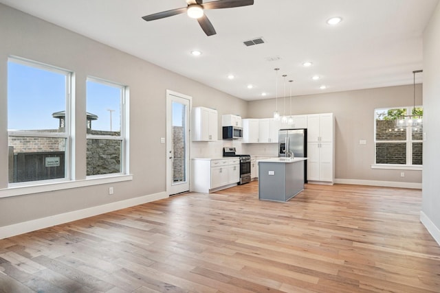 kitchen with white cabinetry, a center island, hanging light fixtures, stainless steel appliances, and light hardwood / wood-style floors