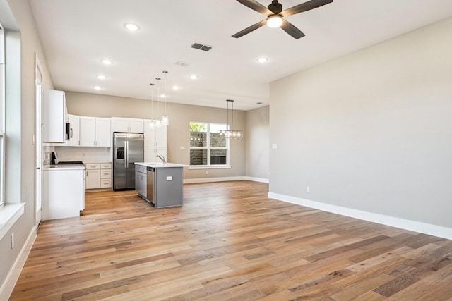 kitchen featuring decorative light fixtures, stainless steel fridge with ice dispenser, light hardwood / wood-style flooring, a kitchen island with sink, and ceiling fan with notable chandelier