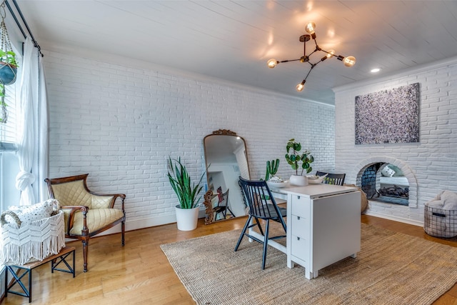 home office featuring a fireplace, light hardwood / wood-style floors, and brick wall