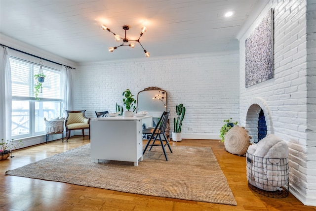 interior space with hardwood / wood-style flooring, brick wall, a chandelier, and a baseboard heating unit