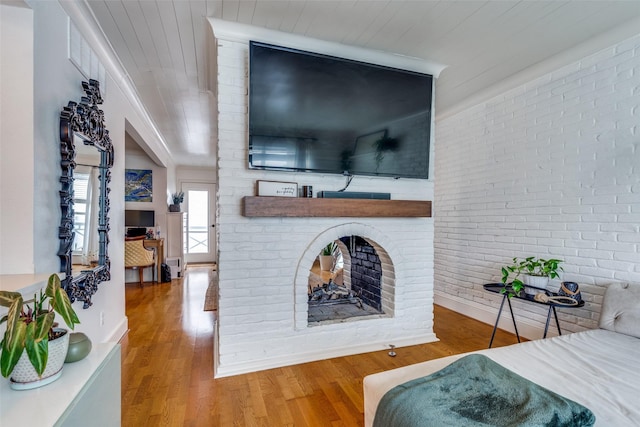 living room featuring wood ceiling, hardwood / wood-style flooring, a fireplace, and brick wall