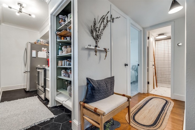 sitting room with ornamental molding and dark wood-type flooring