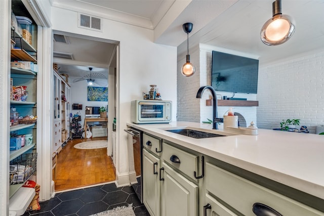 kitchen with brick wall, sink, hanging light fixtures, stainless steel dishwasher, and crown molding