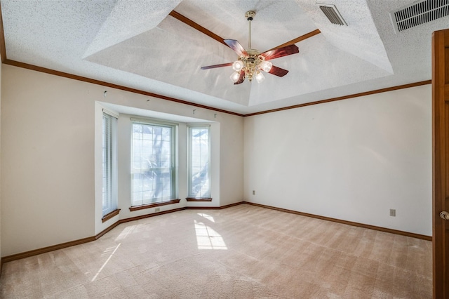 unfurnished room featuring ornamental molding, a raised ceiling, light carpet, and a textured ceiling