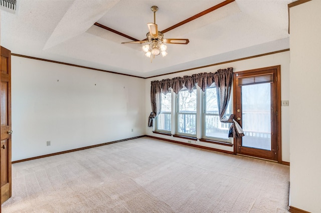 empty room featuring light carpet, a textured ceiling, ornamental molding, a raised ceiling, and ceiling fan