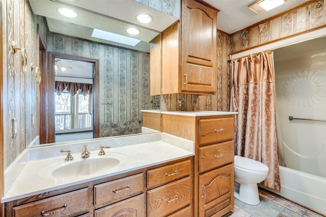 full bathroom featuring toilet, a skylight, a textured ceiling, vanity, and shower / bath combo with shower curtain