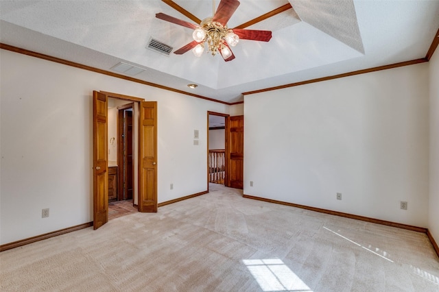 unfurnished bedroom with connected bathroom, light carpet, a textured ceiling, ornamental molding, and a tray ceiling