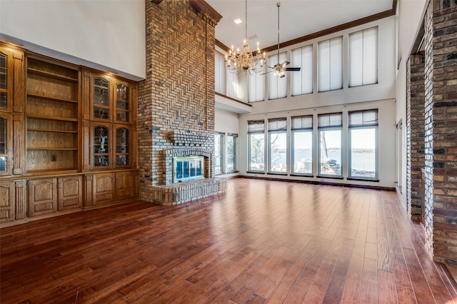 unfurnished living room featuring a brick fireplace, hardwood / wood-style floors, and a notable chandelier