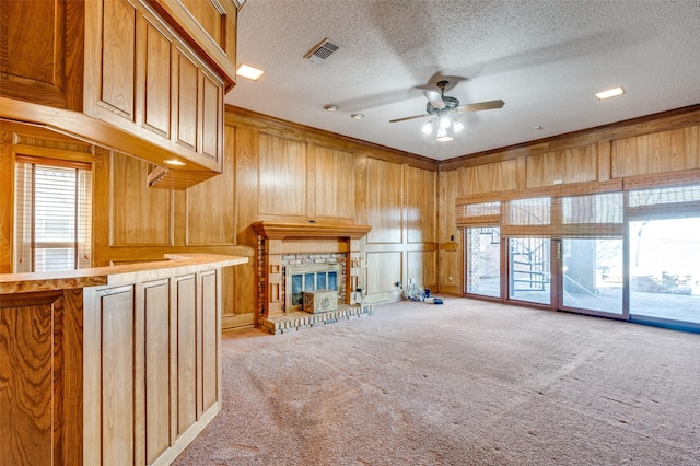 unfurnished living room with wooden walls, light colored carpet, plenty of natural light, and a fireplace