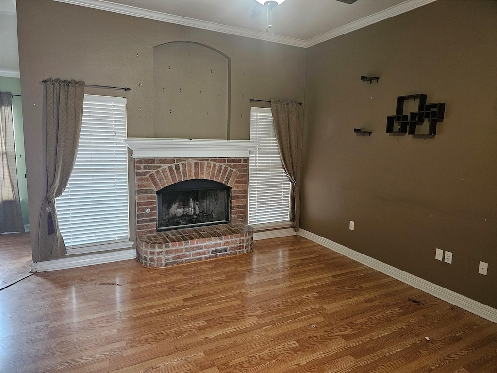 living room featuring wood-type flooring, ornamental molding, and a fireplace