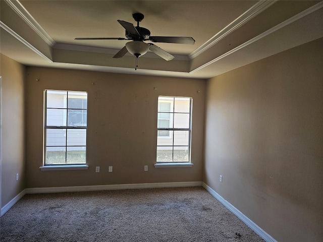 spare room with a tray ceiling, a wealth of natural light, ornamental molding, and carpet