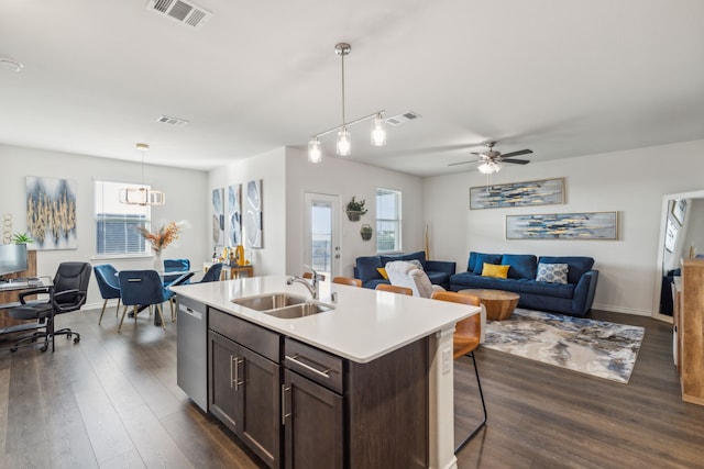 kitchen with pendant lighting, sink, dark brown cabinetry, an island with sink, and stainless steel dishwasher