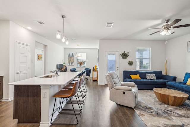 living room featuring ceiling fan, sink, and dark hardwood / wood-style flooring